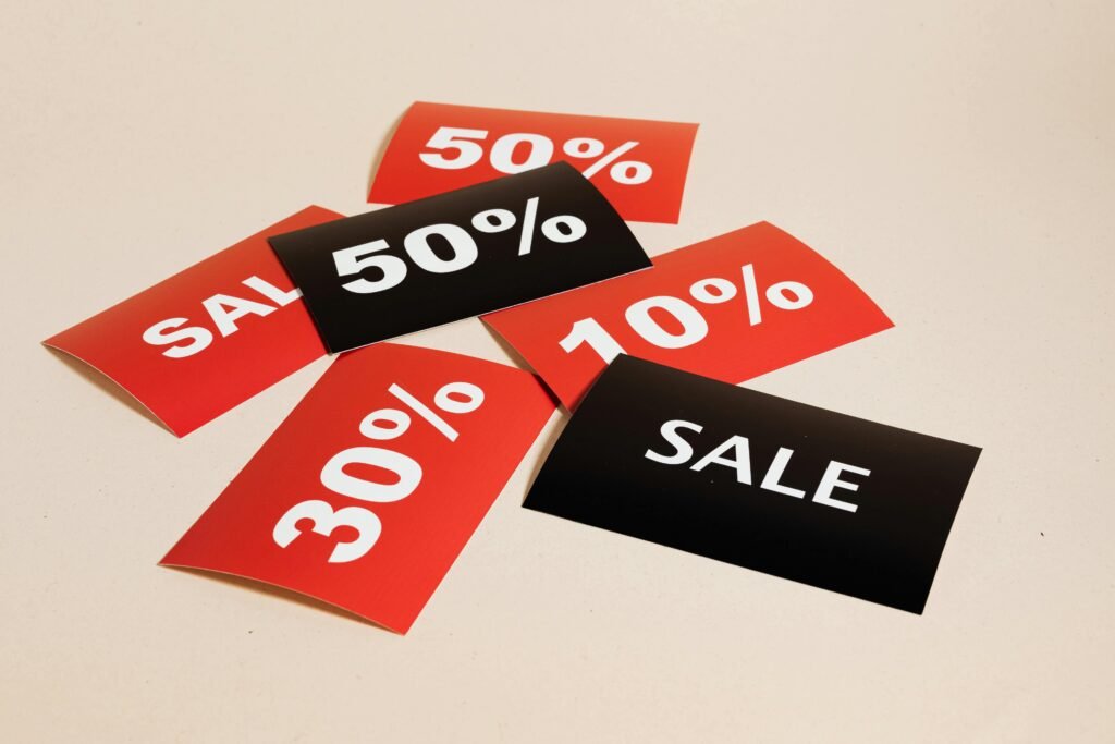 pexels photo 5650026 5650026 Red and black sale tags showing various discount percentages on a beige background.